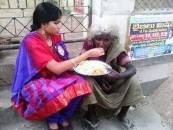 Girl feeding food for poor women